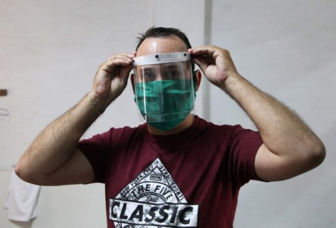Didier Acosta García muestra una de las máscaras protectoras ya terminadas, que de manera artesanal fabrican él y otros dos trabajadores por cuenta propia. Foto: ACN