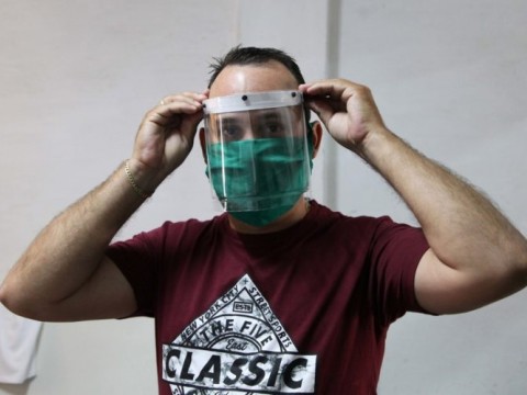 Didier Acosta García muestra una de las máscaras protectoras ya terminadas, que de manera artesanal fabrican él y otros dos trabajadores por cuenta propia. Foto: ACN